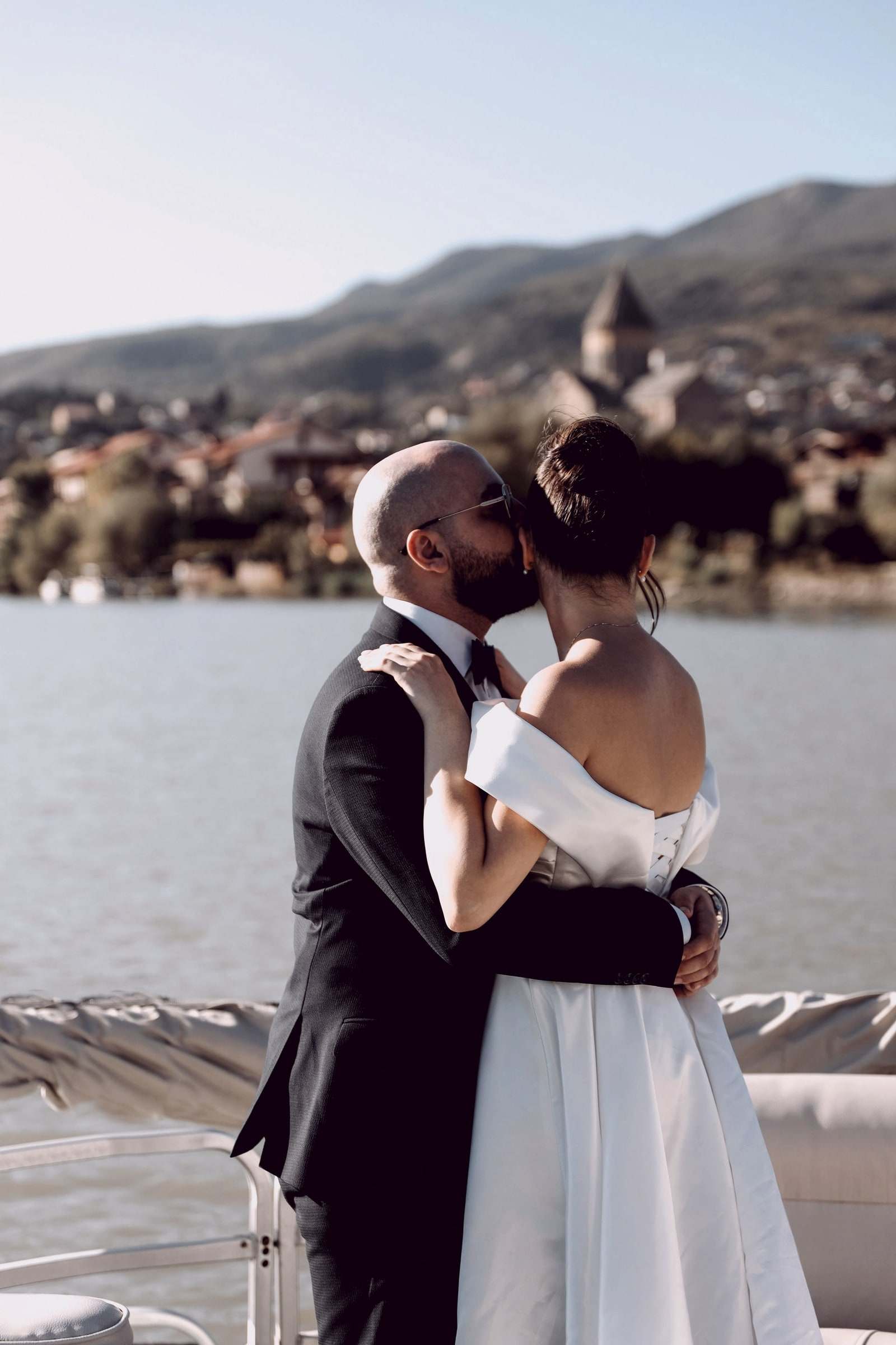 A couple kissing on the bank of the Kura river in Tbilisi, the old town on the hill behind them
